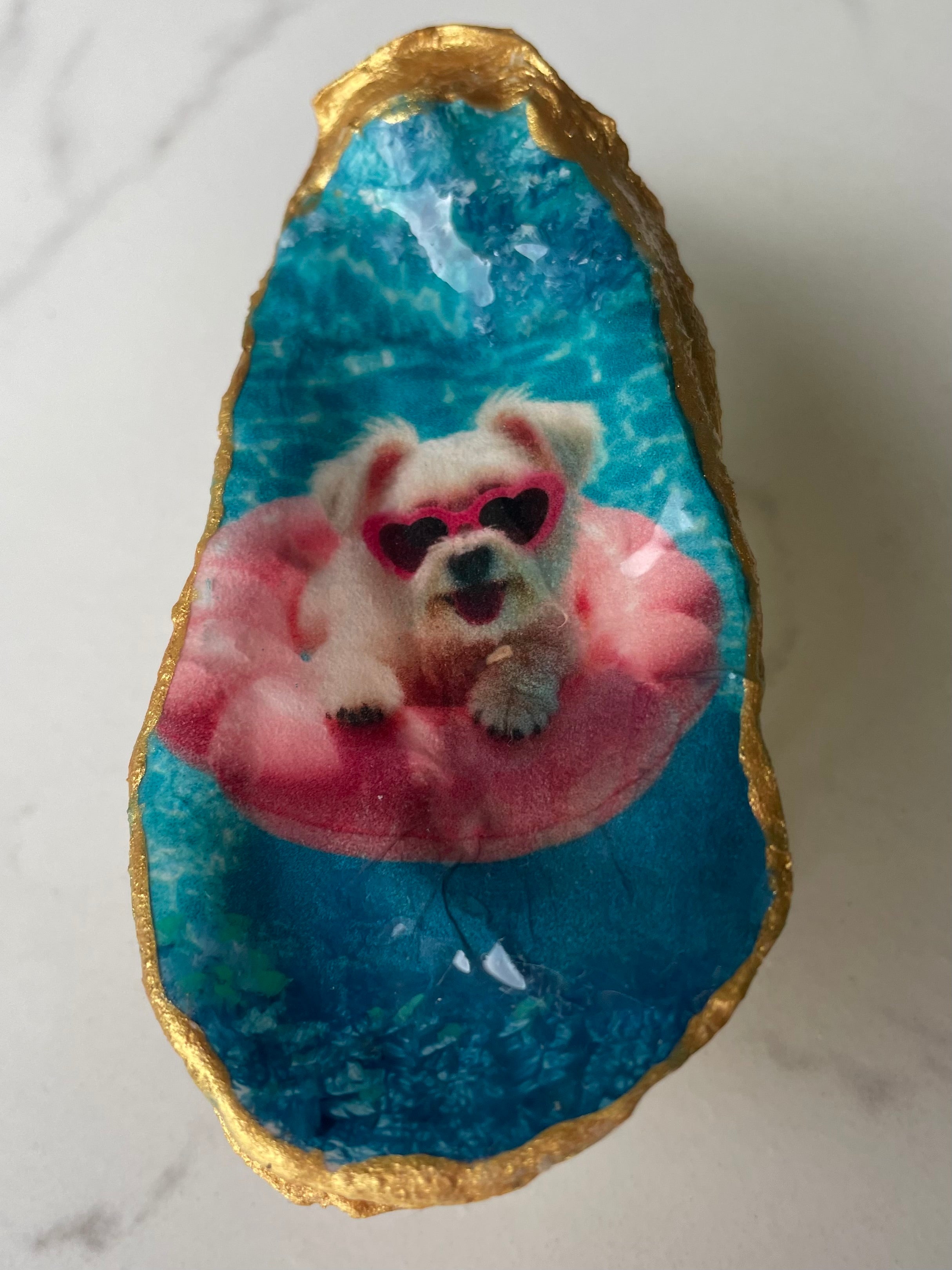 Hero shot of Maltese Poolside Paradise gilded oyster shell ring dish with gold paint edging, displayed on a gold stand