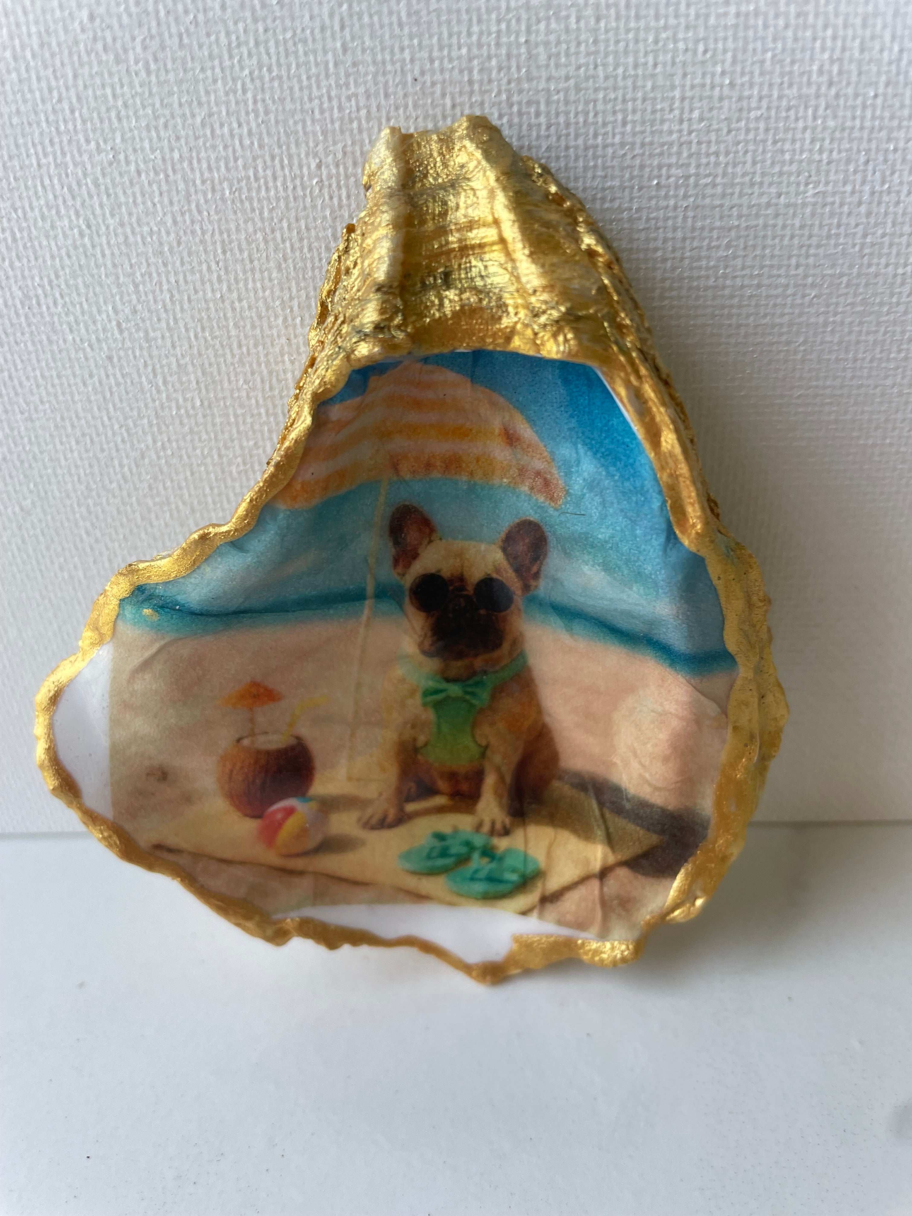 Frenchie Paradise gilded oyster shell ring dish propped up to show artwork — hand-painted French Bulldog beach scene with gold paint edging, handmade by The Golden Shoreline