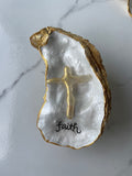 "Faith" Inspiration Series gilded oyster shell trinket dish on gold stand — hand-applied typographic lettering with dimensional gold cross accent, handmade by The Golden Shoreline
