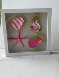 The Flamingo Waltz gilded shell shadowbox — hand-painted pink striped oyster shell, pink starfish with pearl accent, and flamingo decoupage centerpiece with gold paint edges in a white wood shadow box