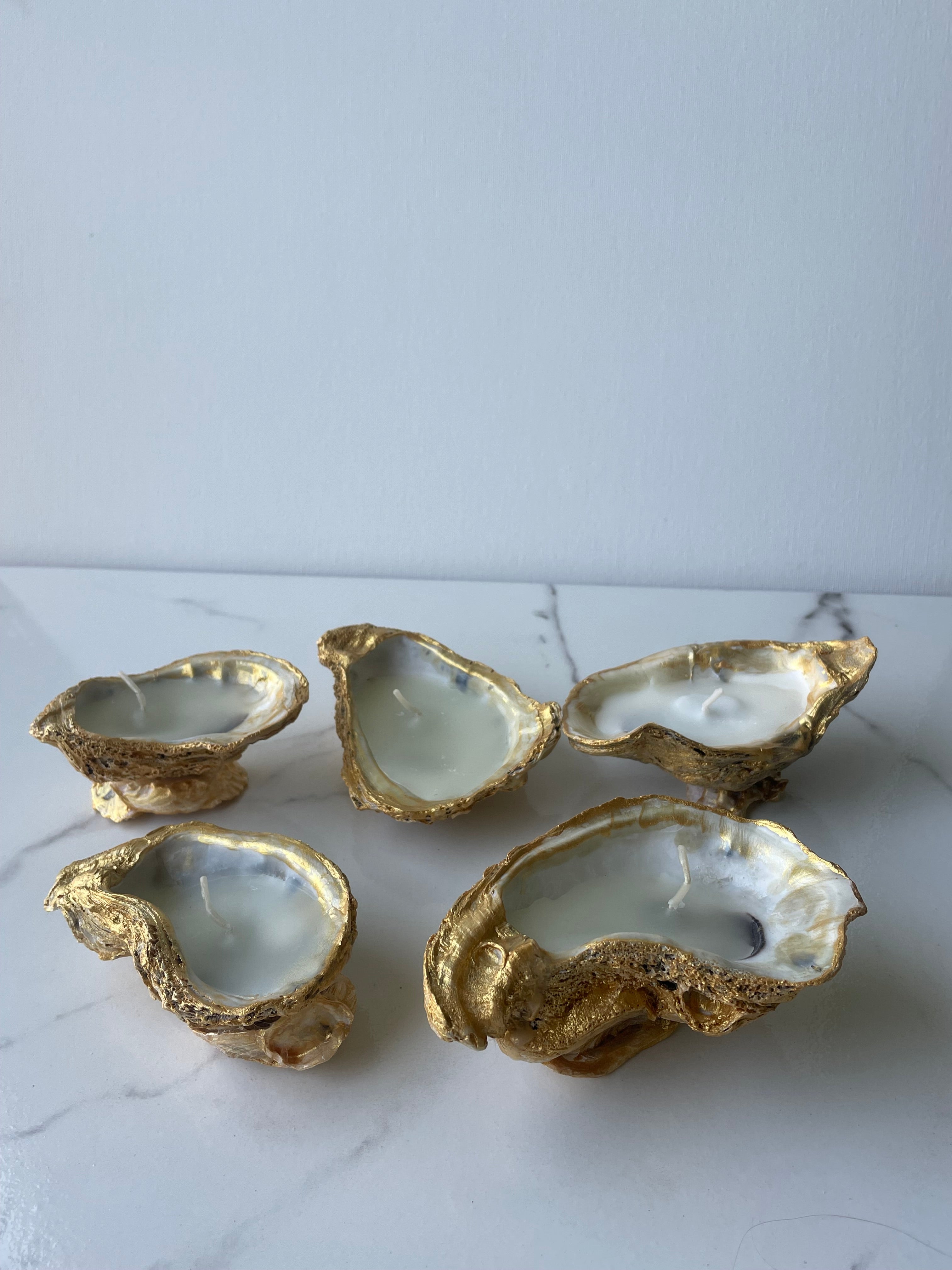 The Shoreline Trio oyster shell candles grouped on a table — handcrafted coastal candles with gold paint edges by The Golden Shoreline