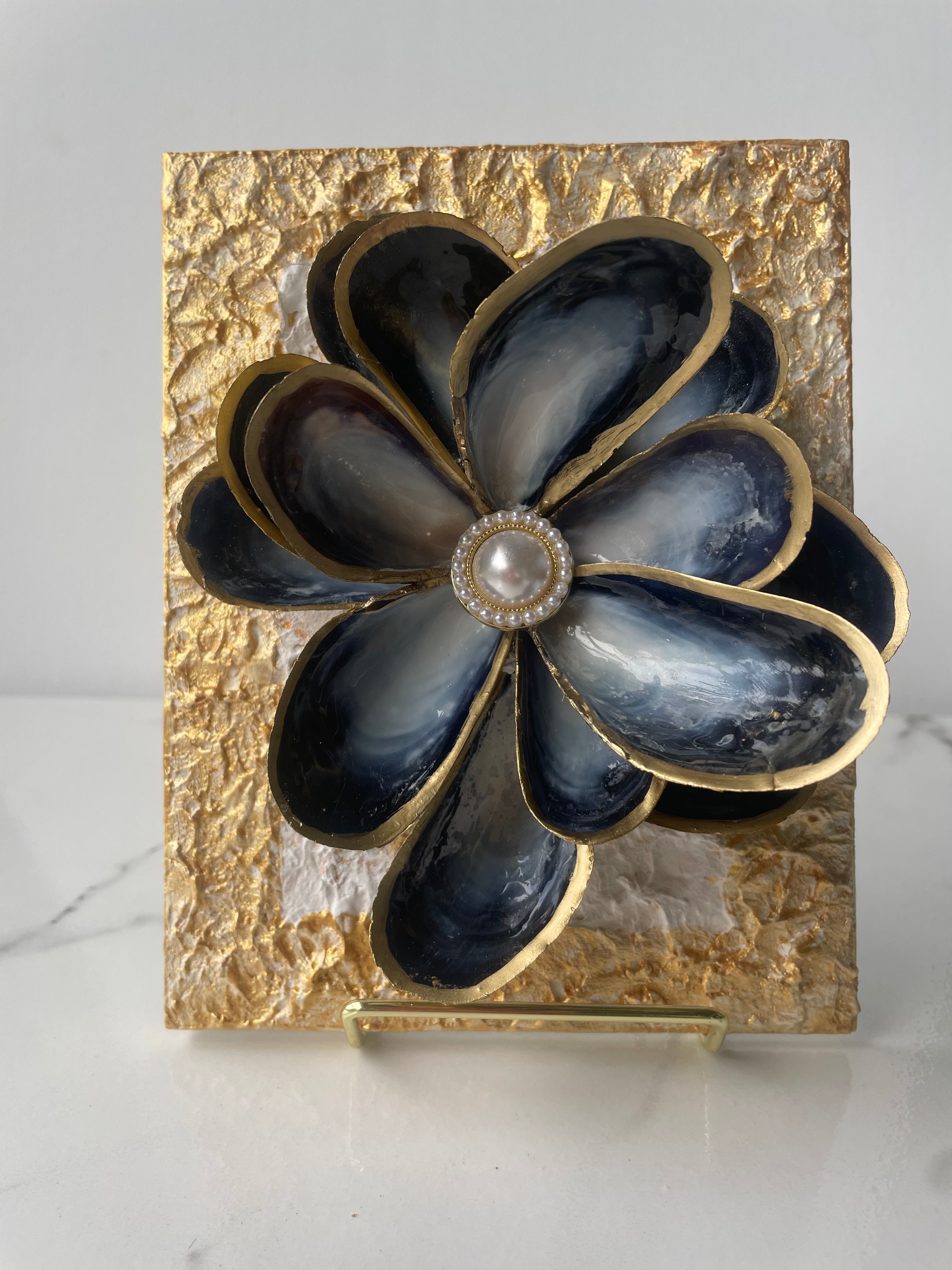 "Handcrafted mussel shell flower with gold paint edges and pearl center, mounted on a textured canvas board — Midnight Bloom by The Golden Shoreline"