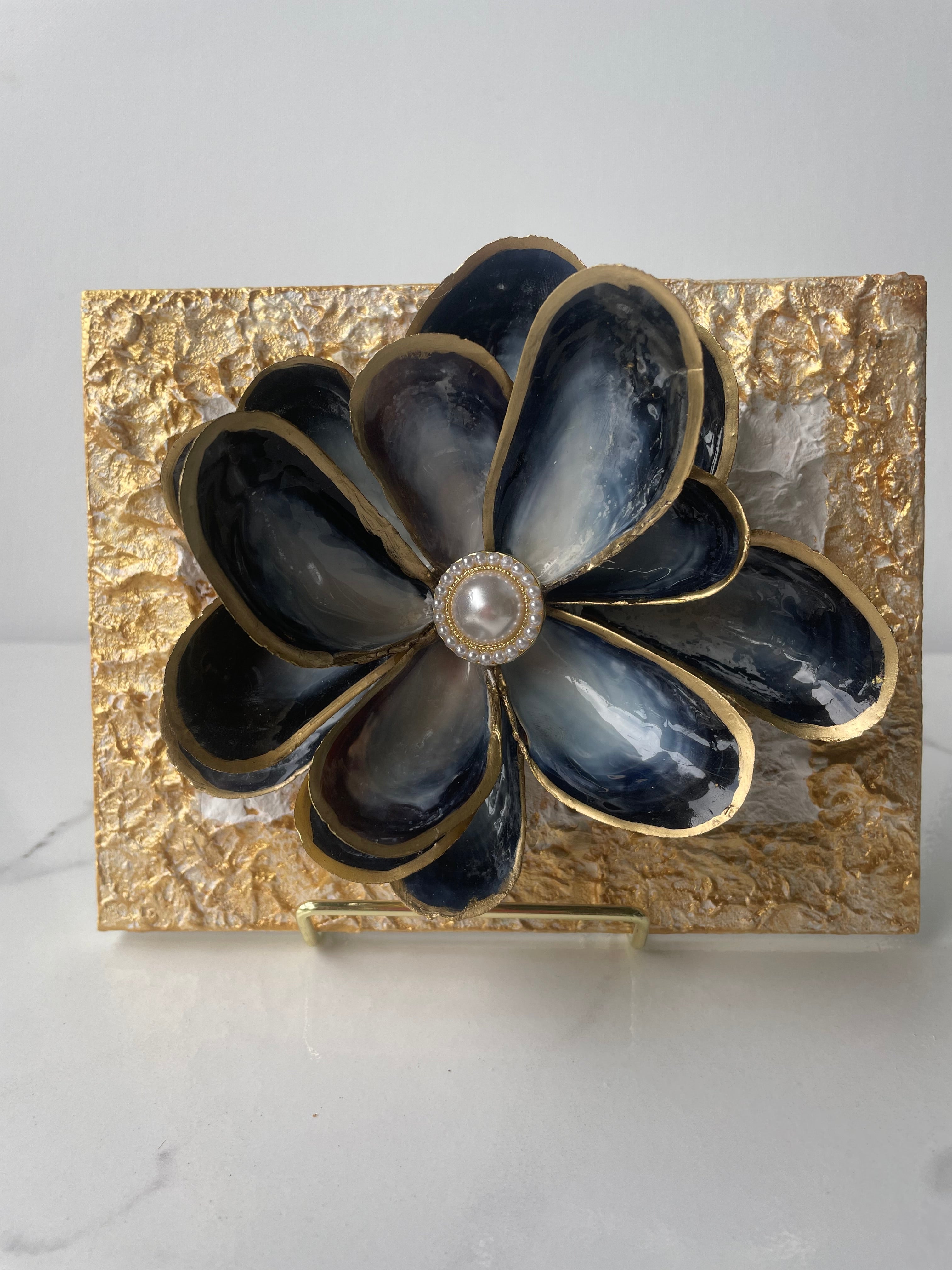"Handcrafted mussel shell flower with gold paint edges and pearl center, mounted on a textured canvas board — Midnight Bloom by The Golden Shoreline"