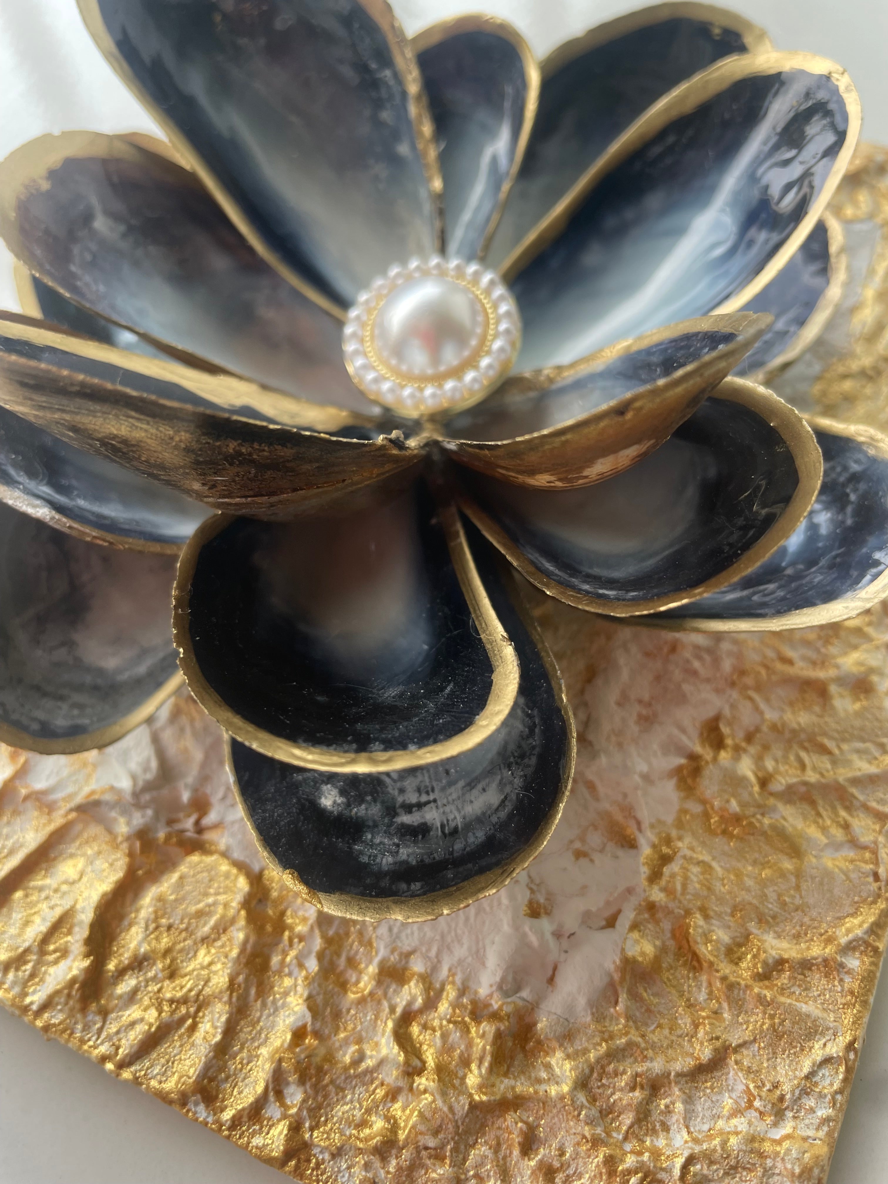 "Handcrafted mussel shell flower with gold paint edges and pearl center, mounted on a textured canvas board — Midnight Bloom by The Golden Shoreline"
