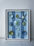 Original coastal wall art with oyster shells, starfish, and gold accents in an 11x14 wood frame". 