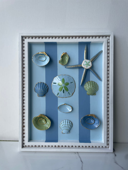 Original coastal wall art with oyster shells, starfish, and gold accents in an 11x14 wood frame". 